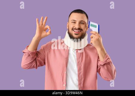 Schöner junger Mann mit Nackenschiene und Infrarot-Thermometer, das OK-Geste auf lilafarbenem Hintergrund zeigt Stockfoto