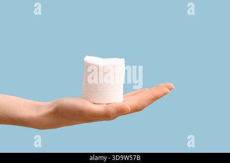 Weibliche Hand mit einem Stapel Wattepads auf blauem Hintergrund, Nahaufnahme Stockfoto