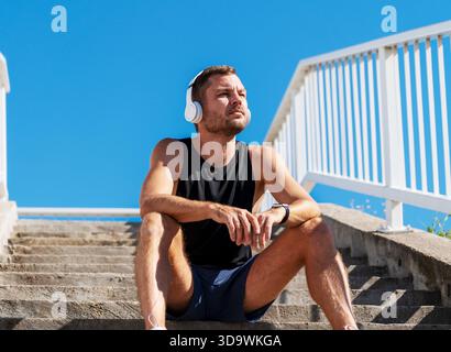 Low-View-Porträt von passendem Mann, der nach dem Training im Freien Kopfhörer trägt. Stockfoto