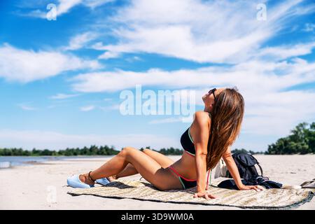 Entspannte Frau, die im Sommer am Sandstrand sonnt Stockfoto