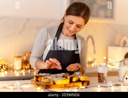Frau, Die Zu Weihnachten Puderzucker Auf Kekse Streut Stockfoto