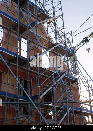 Modernes Wohnhausbauverfahren mit professionellem Metallgerüst und roten Ziegelwänden für Immobilienentwicklung oder Ingenieurbau Stockfoto