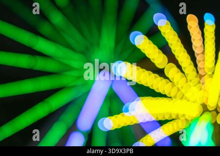 Lebhafte Bokeh-Spiralen eines Nachtwasserrads. Fängt Bewegungsunschärfe, Neonlichter und das flippige Nachtleben der Stadt ein. Stockfoto