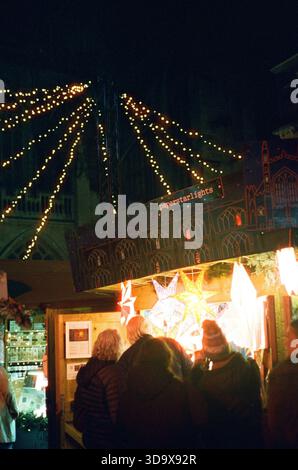 Bath, England - 3. Dezember 2025: Bath Christmas Market, mit Verkaufsständen, Verkaufsständen und Käufern. Aufgenommen nach Einbruch der Dunkelheit auf Spezialfilm. Stockfoto