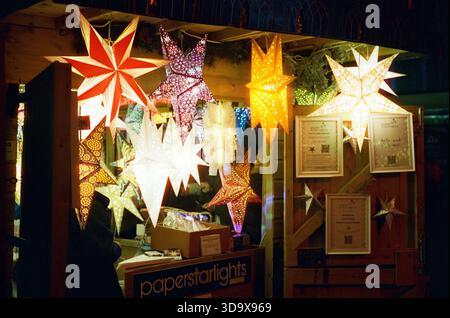 Bath, England - 3. Dezember 2025: Bath Christmas Market, mit Verkaufsständen, Verkaufsständen und Käufern. Aufgenommen nach Einbruch der Dunkelheit auf Spezialfilm. Stockfoto
