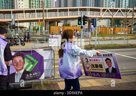 Hongkong, China. Dezember 2025. Der Berater eines Kandidaten zeigt ein Poster seines Kandidaten bei Passanten in der Nähe eines Wahlzentrums in Tin Shui Wai. Die Parlamentswahlen 2025 in Hongkong finden am 7. Dezember 2025 statt, um die 90 Mitglieder des 8. Hongkonger Legislativrates zu wählen. Quelle: SOPA Images Limited/Alamy Live News Stockfoto
