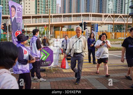 Hongkong, China. Dezember 2025. Der Kandidat verteilt Flugblätter an den Passanten in der Nähe eines Wahlzentrums in Tin Shui Wai. Die Parlamentswahlen 2025 in Hongkong finden am 7. Dezember 2025 statt, um die 90 Mitglieder des 8. Hongkonger Legislativrates zu wählen. Quelle: SOPA Images Limited/Alamy Live News Stockfoto