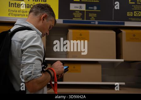 Mann, der ein Telefon in der Nähe des internationalen Versandabschnitts benutzt Stockfoto