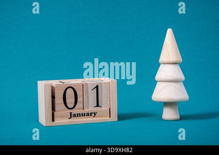 Ein hölzerner Kalender mit dem Datum 1. Januar steht auf blauem Hintergrund. Stockfoto
