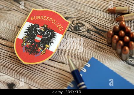 KIEW, UKRAINE - 6. SEPTEMBER 2025 Österreich Bundespolizeiflicken mit Kugeln und Notizblock auf Holztisch Nahaufnahme Stockfoto