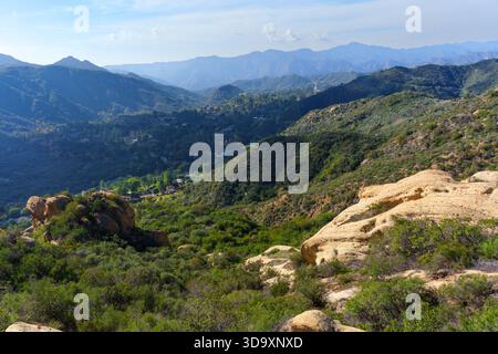 Ein atemberaubendes Panorama fängt die grünen Täler, die weit entfernten Berge und die einzigartigen Sandsteinformationen des Red Rock Canyon ein, die alle im Sonnenlicht unter einem Klo liegen Stockfoto