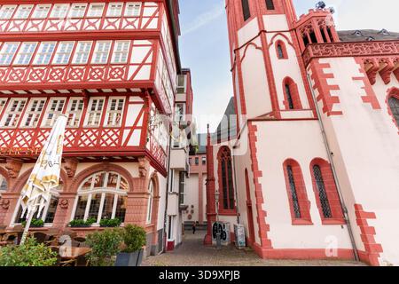Frankfurt, Deutschland - 21. Oktober 2025: Historisches Fachwerkgebäude und eine majestätische gotische Kirche stehen markant entlang einer charmanten Kopfsteinpflasterstraße Stockfoto