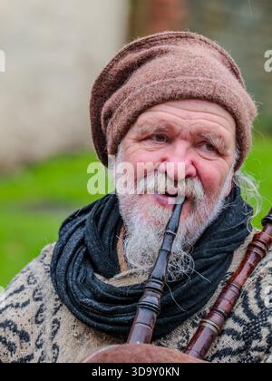 Dickens Christmas Festival Rochester UK Dezember 2025. Bärtiger Mann spielt im Freien traditionelle Dudelsack in rustikaler Umgebung und trägt Volkskleidung Stockfoto