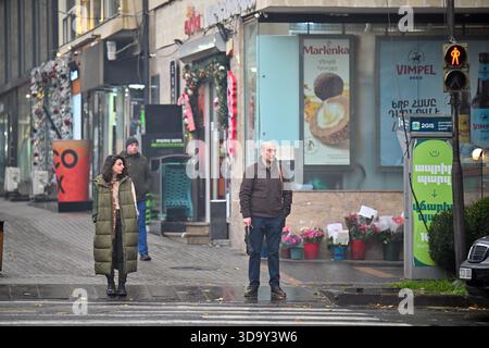 Jerewan Armenien 12.7,2025. Ein Mann und eine Frau stehen im Regen an einem Quersteg. Der Mann hält ein Handy und die Frau trägt ein Grün Stockfoto