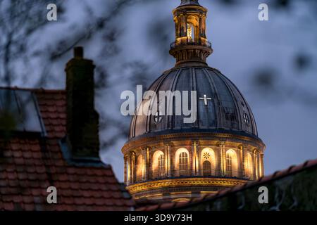 Beleuchtete Kuppel der Basilika Notre-Dame de Boulogne-sur-Mer, die in der Abenddämmerung über den Dächern der Altstadt leuchtet. Abendblick auf die historische Basilika. Stockfoto