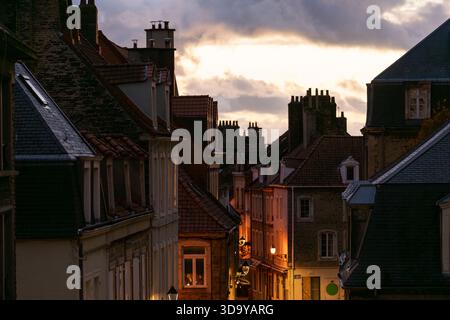 Abendlicher Blick auf die Straßen der Altstadt in Boulogne-sur-Mer, beleuchtet durch warmes Laternenlicht bei Sonnenuntergang. Historische Dächer und enge Gassen. Stockfoto