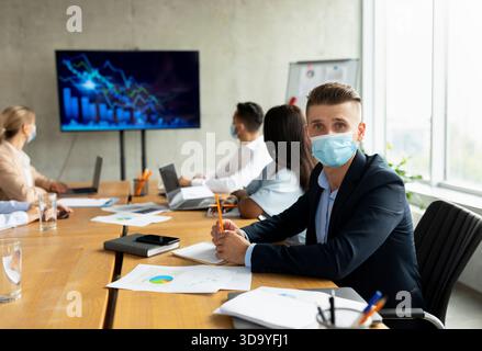Multiethnisches Business-Team in Masken, das während der Gesundheitskrise im Büro zusammenarbeitet Stockfoto