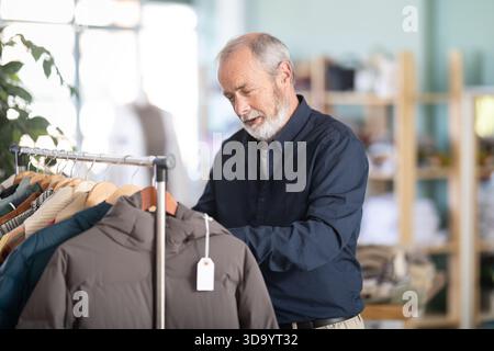 Ein älterer Mann sucht sich eine Daunenjacke in einem Geschäft aus Stockfoto