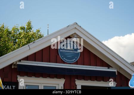 Nynashamn, Stockholmer County, Schweden – 29. Mai 2025: Ein rotes Gebäude mit einem blauen Schild, auf dem Skargardsbutiken in weißen Buchstaben steht. Das Gebäude ha Stockfoto