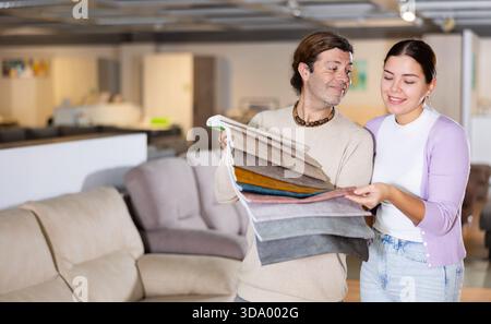 Der Mann präsentiert einer Frau Polstermuster Stockfoto