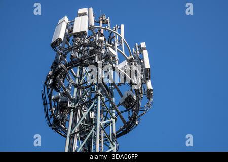 Ein hoher Mobilfunkmast, der vor einem klaren blauen Himmel erfasst wurde und moderne Mobilfunknetzinfrastruktur und Telekommunikationsausrüstung zeigt Stockfoto
