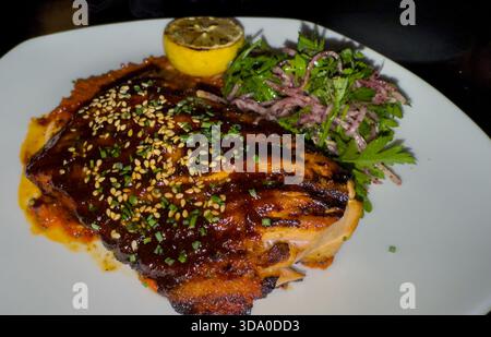Gegrilltes Honig-Harissa-Lachsgericht mit Salat und Zitrone. Libanesischer Cousin Stockfoto