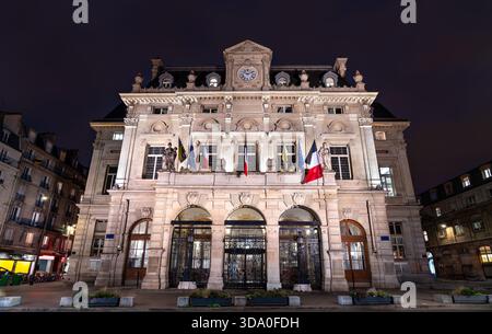 Rathaus des 18. Arrondissements in Paris, Frankreich. Das historische Gebäude mit Uhrenturm und Fahnen steht nachts am Place Jules Joffrin Stockfoto