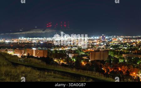 Ein Nachtblick auf Billings, Montana. Die Ölraffinerie ist hell beleuchtet unter den Klippen von Rimrocks, die von hohen roten Antennentürmen gekrönt sind Stockfoto