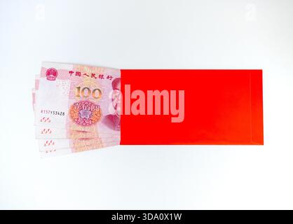 Roter Umschlag ANG BAO mit 100 chinesischen Yuan-Banknoten auf weißem Hintergrund. Chinesisches Neujahr, Geschenkgeld, Gehaltsbonus, finanzieller Segen, Wohlstand, Stockfoto