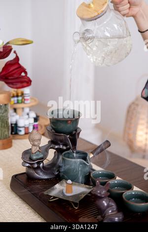 Teegießen. Heißgetränk. Frau Hände füllen Glas Teekanne mit erfrischenden Flüssigkeit gesunden Lebensstil Weihrauch brennen. Stockfoto