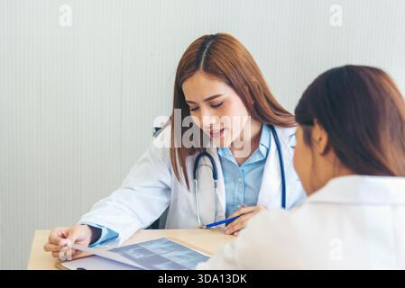 Zwei asiatische Ärztinnen diskutieren Besprechung Arztpraxis medizinische Klinik mit Laptop Beratung Patientenkrankheit. Asiatisches medizinisches Labor, junge Frauen im Gespräch Stockfoto