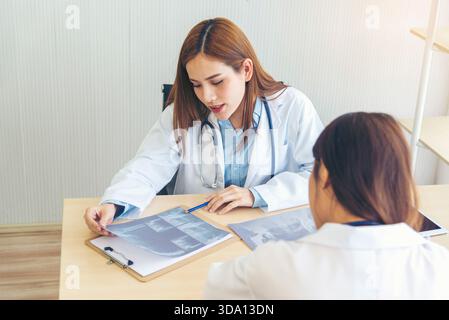 Zwei asiatische Ärztinnen diskutieren Besprechung Arztpraxis medizinische Klinik mit Laptop Beratung Patientenkrankheit. Asiatisches medizinisches Labor, junge Frauen im Gespräch Stockfoto