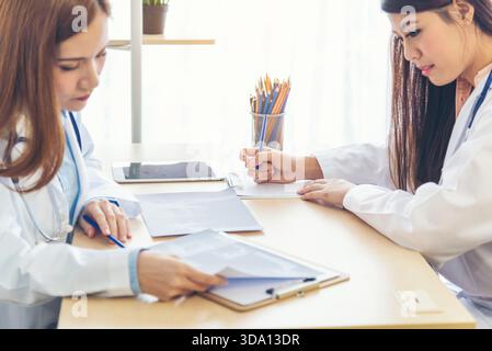 Zwei asiatische Ärztinnen diskutieren Besprechung Arztpraxis medizinische Klinik mit Laptop Beratung Patientenkrankheit. Asiatisches medizinisches Labor, junge Frauen im Gespräch Stockfoto