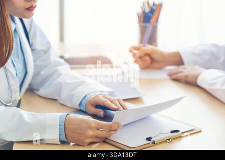 Zwei asiatische Frauen Hand Ärzte Treffen schreiben verschreibungspflichtige medizinische Klinik. Arzt besprich mit dem Laptop einen schriftlichen Hinweis. Nahhände von zwei Frauen, Doktor med Stockfoto