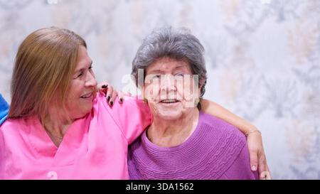 Krankenschwester, die glückliche Großmutter im Pflegeheim umschließt Stockfoto