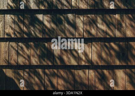 Traditionelle hölzerne Dachziegel in alpiner Architektur mit Sonnenlicht und Schatten, die ein rustikales Oberflächenmuster schaffen. Draufsicht. Stockfoto