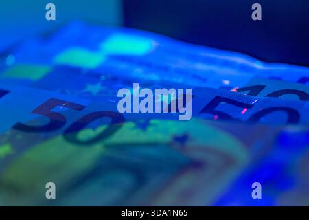 Nahaufnahme farbenfroher Euro-Banknoten, beleuchtet durch blaue Lichteffekte Stockfoto