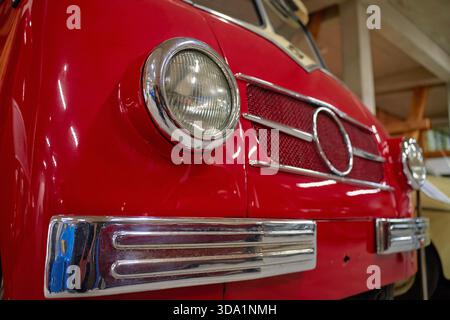 Nahaufnahme der Oldtimer-Front in Rot mit Scheinwerfer und verchromtem Kühlergrill. Konzept des Retro-Fahrzeugdesigns Stockfoto
