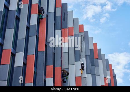 Fensterreiniger zur Reinigung der Fenster an der Fassade moderner Bürogebäude. Hochhohe Fensterreiniger mit Seilzugang. Industrialpinisten waschen das Äußere von Wolkenkratzern. Gefährliche Arbeiten in der Höhe Stockfoto
