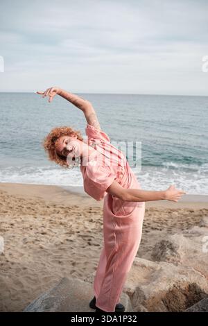 Frau, die frei am Strand tanzt und einen Jumpsuit trägt Stockfoto