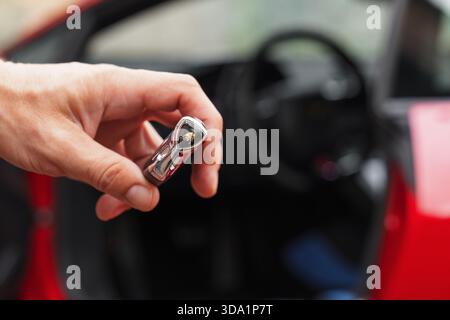 Slowenien, Ljubljana - 9. Oktober 2025: Lamborghini Huracan STO-Schlüssel in der Hand in der Nähe der geöffneten Autotür Stockfoto