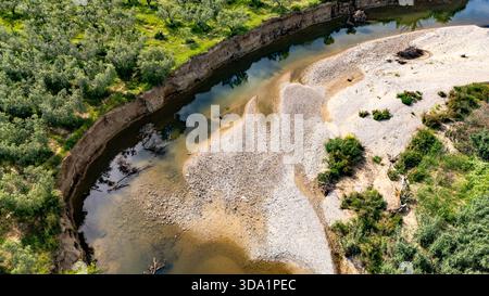 Blick von der Drohne auf den Fluss Vatonia, der im Frühjahr durch Olivenhaine in der Nähe von Kalyves, Chalkidiki, Griechenland fließt. Malerische mediterrane Landschaft mit Stockfoto