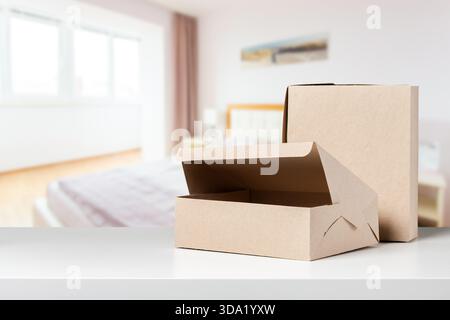 Pappkartons auf einem Tisch in einem hellen Schlafzimmer tagsüber Stockfoto