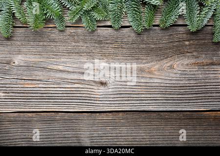 Weihnachten oder Neujahr Hintergrund mit einem Rand von grünen Tannenzweigen. Rustikaler hölzerner Ornament-Hintergrund Stockfoto