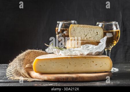 Auswahl an Käsesorten mit eleganten Gläsern Wein auf einem rustikalen Holztisch Stockfoto