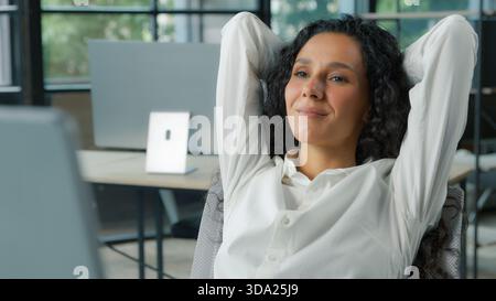 Entspannte glückliche hispanische Geschäftsfrau im Büro Hände hinter Kopf Ruhepause lächelnde positive Geschäftsfrau entspannen träumen Denken Stockfoto