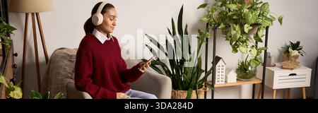 Eine junge Frau genießt einen friedlichen Moment zu Hause und hört Musik, während sie von Pflanzen umgeben ist Stockfoto