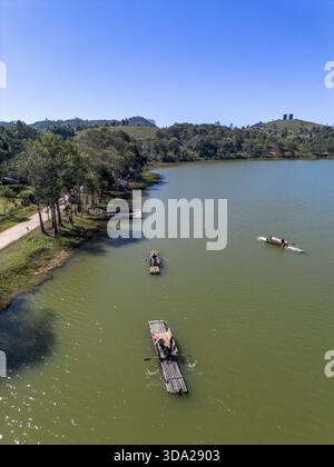 Ruhige Aussicht auf die wunderschöne Seenlandschaft mit Bambusfloß auf grünem Wasser. Menschen genießen friedlichen Sommerurlaub an sonnigen Tagen mit blauem Himmel und Stockfoto