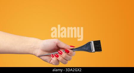 Malwerkzeuge in der Hand gehalten mit leuchtend orangefarbenem Hintergrund während einer Kunst- und Handwerkstätigkeit Stockfoto