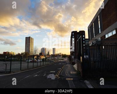Salford, Großbritannien - 8. November 2025: Abendlicht über den Straßen von Salford mit Backsteinhäusern, Zäunen und geparkten Autos. Stockfoto